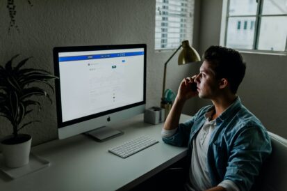 man sitting at a desk in a dim room looking at the screen 