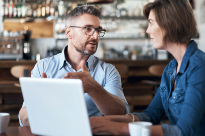 two people talking in a café at a laptop