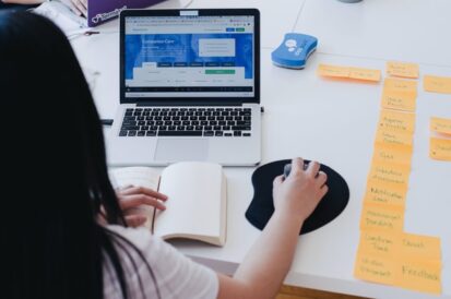 woman working at a desk on her laptop with a notebook