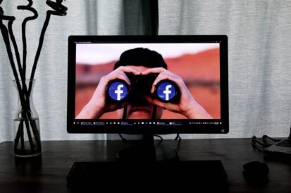 man looking through binoculars seeing facebook logo