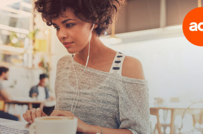 woman with headphones in working on a laptop with the act! CRM logo in the top right corner